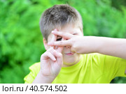 Boy shows sign gesture prison bars outdoors. Стоковое фото, фотограф Володина Ольга / Фотобанк Лори