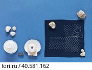 Top view of the process of hand Sashiko embroidery in Japanese style with white threads on blue cotton fabric on blue background. DIY concept. Flat lay, closeup, white background, mock up. Стоковое фото, фотограф Виктория Катьянова / Фотобанк Лори