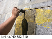 Ремонт здания, реконструкция, предварительные работы. Man's hand is brushing along the wall. Rough wall finishing. Стоковое фото, фотограф Iva Noel / Фотобанк Лори