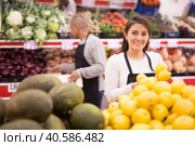 Merchandiser lays out ripe lemons on the shelves in supermarket. Стоковое фото, фотограф Яков Филимонов / Фотобанк Лори