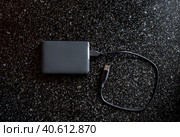 External hard drive in a black case with a wire on a black background. Useful portable storage device, high speed portable device. Стоковое фото, фотограф Коханова Наталья / Фотобанк Лори