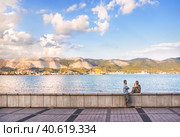 Парочка на закате и солнечный порт, Черное море, набережная Адмирала Серебрякова, Краснодарский край, Новороссийск (2022 год). Стоковое фото, фотограф Baturina Yuliya / Фотобанк Лори