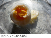 Вареное надкусанное куриное яйцо/ Boiled peeled bitten egg with a piece of butter on a transparent plate. Стоковое фото, фотограф Iva Noel / Фотобанк Лори