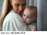 Adorable newborn baby on hands loving happy mother at home, looking away. Mommy with kid together in room. Mum care 6 months old infant child. Concept of motherhood, maternity. Copy ad text space. Стоковое фото, фотограф Aleksandr Golubev / Фотобанк Лори