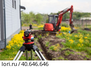 Нивелир для земляных работ на фоне миниэкскаватора. Стоковое фото, фотограф Кекяляйнен Андрей / Фотобанк Лори