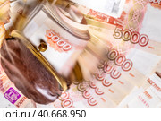 Пачка рублевых пятитысячных купюр лежит в старом кошельке на фоне денежных купюр, в расфокусе. Стоковое фото, фотограф Николай Винокуров / Фотобанк Лори