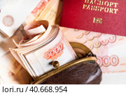 Заграничный паспорт гражданина РФ и старый кошелек набитый пятитысячными купюрами лежит на столе на фоне пятитысячных рублевых купюр. Стоковое фото, фотограф Николай Винокуров / Фотобанк Лори