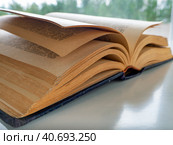 An old thick book is open and lies diagonally on a light table. Background with a book for libraries, education, scientific work, university. Стоковое фото, фотограф Бузмакова Светлана / Фотобанк Лори