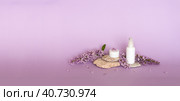 Moisturizing natural cosmetics for facial skin care with flower extract and lilac aroma. Jar of cream, spray, fresh lilac flowers on pedestal of stones on pastel pink background. Advertising of cosmetic products. Стоковое фото, фотограф Виктория Катьянова / Фотобанк Лори