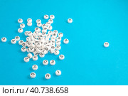 Кучка рассыпанных пластиковых круглых деталей с английскими буквами. A pile of scattered white little round chips with black English letters to form words. Blue background. Стоковое фото, фотограф Валерий Елистратов / Фотобанк Лори