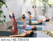 Parents with children lie on backs on karemat and hold softball with legs raised up. Стоковое фото, фотограф Яков Филимонов / Фотобанк Лори