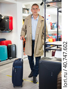 Positive man chose suitcase in haberdashery store. Стоковое фото, фотограф Яков Филимонов / Фотобанк Лори