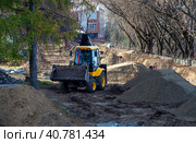 Backhoe loader drives past heaps of soil and dug trenches. Background with tractor at the construction site. Стоковое фото, фотограф Бузмакова Светлана / Фотобанк Лори