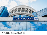 Saransk, Mordovia, Russia, 4.06.2023. The blue facade of the building with the inscription Russian Post and a double-headed Russian eagle, against the background of the reflection of clouds on the glass surface. Редакционное фото, фотограф Оксана Медведева / Фотобанк Лори