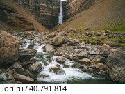 Hengifoss waterfall in East Iceland. Hengifoss is the third highest waterfall in Iceland and is surrounded by basaltic strata with red layers of clay between the basaltic layers (2020 год). Стоковое фото, фотограф Igor Tichonow / Фотобанк Лори