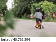 A cheerful little boy rides a running bike in a helmet outdoors. A happy child is engaged in an active sport. Protection. Life insurance and child safety. Стоковое фото, фотограф Photojuli / Фотобанк Лори