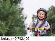 A cheerful little boy rides a running bike in a helmet outdoors. A happy child is engaged in an active sport. Protection. Life insurance and child safety. Стоковое фото, фотограф Photojuli / Фотобанк Лори