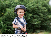A cheerful little boy rides a running bike in a helmet outdoors. A happy child is engaged in an active sport. Protection. Life insurance and child safety. Стоковое фото, фотограф Photojuli / Фотобанк Лори