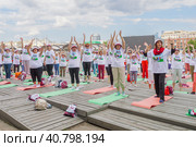 Московские пенсионеры в фирменных московских футболках и головных уборах делают гимнастику в парке Музеон на фоне Крымского моста, голубого неба и красивых кучевых облаков во время спортивного праздника программы «Московское долголетие» (2023 год). Редакционное фото, фотограф Сергей Никифоров-Гордеев / Фотобанк Лори