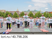Женщины пенсионерки в фирменных московских футболках и головных уборах в московском парке Музеон выполнят гимнастику, стоя на разноцветных гимнастических ковриках (2023 год). Редакционное фото, фотограф Сергей Никифоров-Гордеев / Фотобанк Лори