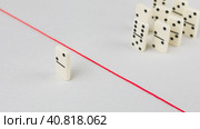 Expelled from the group, unable to cross the red line that separates them. Scene with group of domino. Concept of accusation guilty person, bulling or outcast in the team. Bright background. Стоковое фото, фотограф Igor Tichonow / Фотобанк Лори