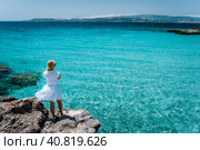 Jung adult women in white dress on summer vacation in front of sea coast landscape of small beach with crystal clear blue water. Greece, Kefalonia. Стоковое фото, фотограф Igor Tichonow / Фотобанк Лори