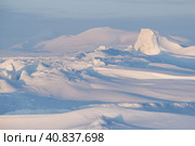 Winter arctic landscape. Ice hummocks on the frozen sea in the Arctic. Cold frosty winter weather. Harsh polar climate. View of snow-covered ice and snow-capped mountains. Amazing nature of the Arctic. Стоковое фото, фотограф Андрей Степанов / Фотобанк Лори