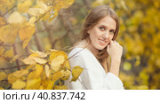 Beautiful young woman with light brown hair in a white sweater on a background of foliage in an autumn park. Portrait of an attractive happy woman among colorful yellow leaves. Fall season. Autumn. Стоковое фото, фотограф Андрей Степанов / Фотобанк Лори