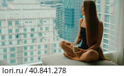 Young smiling woman drinking delicious coffee near window with big city skyscrapers outside. Relaxed girl enjoys morning cappuccino on weekend in the metropolis. Slow motion close-up footage. Стоковое фото, фотограф Ольга Сухарева / Фотобанк Лори