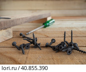Self-tapping screws on a wooden surface and a wooden background. Selective focus. Construction and repair work. Black screws. Стоковое фото, фотограф Александр Кротков / Фотобанк Лори