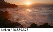 Orange sunset light reflected on stormy ocean waves at rocky coastline. Sea water foam crash in slow. Стоковое видео, видеограф Ольга Сухарева / Фотобанк Лори