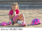 Little girl preschool sitting wearing her roller skates and crossing her legs. children's hobby. sports lifestyle. Стоковое фото, фотограф Ирина Михайличенко / Фотобанк Лори
