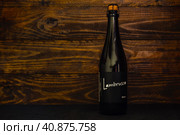 A bottle of Italian Lambrusco Bianco sparkling wine on a dark wooden background. Wine drink carbonated white semi-sweet. (2021 год). Редакционное фото, фотограф Воловодов Владимир / Фотобанк Лори