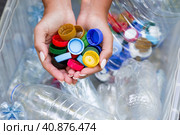 A woman's hands hold the lids of plastic bottles for recycling and environmental conservation, reuse, garbage disposal. Clean the planet of plastic garbage. Стоковое фото, фотограф Photojuli / Фотобанк Лори