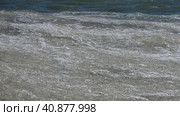 Sea waves from the snow and ice mass roll along the shore. Ice with snow floats on the sea waves near the shore. Sea waves with a snowy ice mass run up to the shore, covered with small ice floes. Стоковое видео, видеограф Александр Кротков / Фотобанк Лори