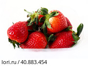 Ripe strawberries in a plastic package on a white background. Delicious fresh berries in a container for sale to customers. Keeping food fresh. Healthy food, vitamins and microelements. Стоковое фото, фотограф Юлия Петровская / Фотобанк Лори