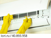 Руки в желтых перчатках извлекают воздушный фильтр кондиционера для очистки. Концепт домашней работы или работы технического специалиста сервисной компании. Стоковое фото, фотограф Светлана Ельцова / Фотобанк Лори