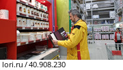 Buyer selects paint and plaster in the store (2018 год). Редакционное фото, фотограф Анна Кривицкая / Фотобанк Лори