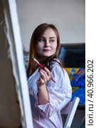 Lovely young woman painter painting with oil paints on canvas in art studio at home, pensive looking away. Portrait of pretty woman artist sits in lab with brush. Lifestyle concept. Copy ad text space. Стоковое фото, фотограф Aleksandr Golubev / Фотобанк Лори