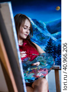 Lovely woman painter in red shirt painting with brush oil paints on canvas in art lab, pensive looking. Portrait of pretty drawing woman artist. Artisanal lifestyle concept. Copy ad text space. Стоковое фото, фотограф Aleksandr Golubev / Фотобанк Лори