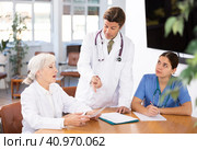 three positive doctors are sitting at table animatedly and actively discussing current work. Стоковое фото, фотограф Яков Филимонов / Фотобанк Лори