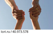 Adult holding a child by the hand on blue sky background. Parent hand reaches out to help child hand in need. Kids Shaking Hands. Children's hand reaches for a daddy. family united. Handshake. Стоковое видео, видеограф Марина Демидюк / Фотобанк Лори