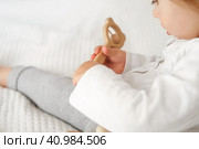 Cute baby girl playing tactile wooden and silicone toys. Young child hand plays sensory massage ball. Enhance the cognitive, physical process. Brain development. Teething toy. Dentition. Baby's teeth. Стоковое фото, фотограф Марина Демидюк / Фотобанк Лори