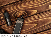 Vape and vape juice bottles on brown wooden background. Стоковое фото, фотограф Сергей Толмачёв / Фотобанк Лори