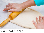 Woman's hands with a dough. A woman rolls out a piece of dough with a wooden rolling pin. Женские руки с тестом. Женщина раскатывает кусок теста деревянной скалкой. Стоковое фото, фотограф Дмитрий Березнев / Фотобанк Лори