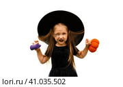 Portrait of winsome little witch angry upset girl wearing a wizard hat and dressed in stylish carnival dress, looking at camera posing against white background, Halloween. Стоковое фото, фотограф Ирина Старикова / Фотобанк Лори