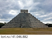 Unique pyramid of Kukulkan in the cloudy sky. An ancient stone ritual stepped building with a staircase. The left side has not been restored and looks dilapidated. Wonder of the World. Unesco heritage (2018 год). Стоковое фото, фотограф Вера Ивановна Кубарева / Фотобанк Лори