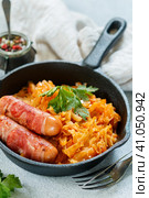 Stewed cabbage with carrots, onions and tomatoes and sausages in bacon with parsley and spices in a cast iron pan. Bigos. Delicious lunch. Стоковое фото, фотограф Виктория Панченко / Фотобанк Лори