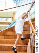 Rear view of joyful blonde little girl 5-6 year old in white dress climbs stairs to top. Shot of funny child girl going steps up, rear view from behind. Happy childhood concept. Copy ad text space. Стоковое фото, фотограф Aleksandr Golubev / Фотобанк Лори