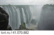 The powerful streams of the Zambezi River plunge into the abyss. The fog is over the gorge. Wet boulders in the foreground. Victoria Falls. Zimbabwe. (2020 год). Стоковое фото, фотограф Вера Ивановна Кубарева / Фотобанк Лори